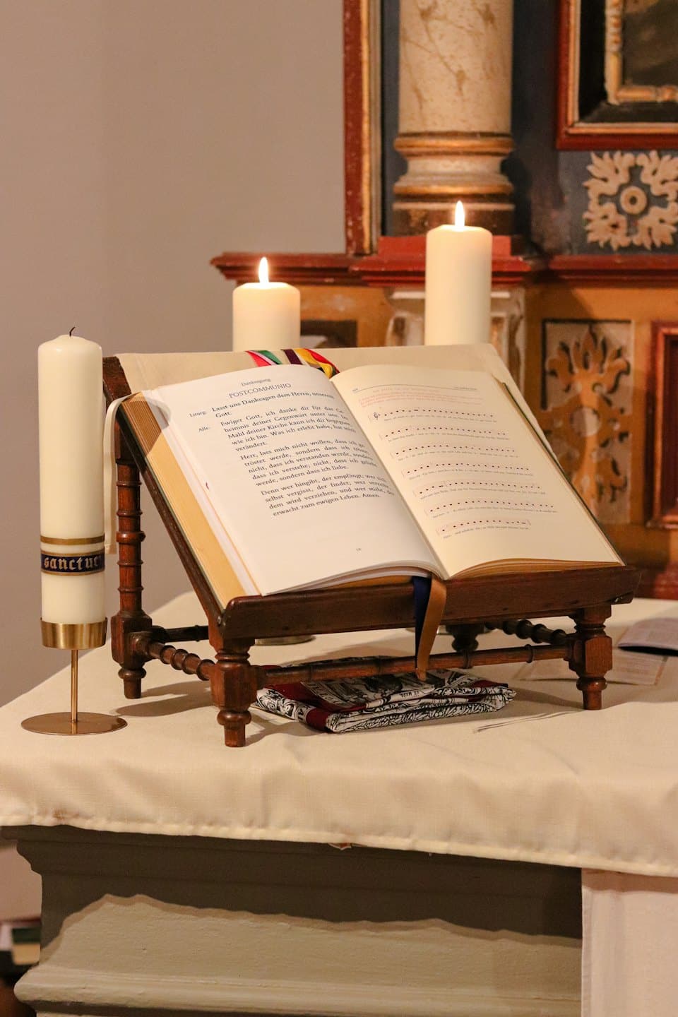 Un libro di preghiere aperto riposa su un leggio accanto a candele accese.