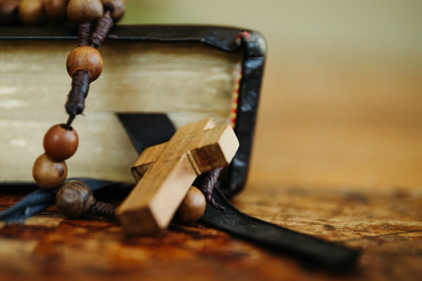 Rosario di legno appoggiato su un libro rilegato in pelle scura.