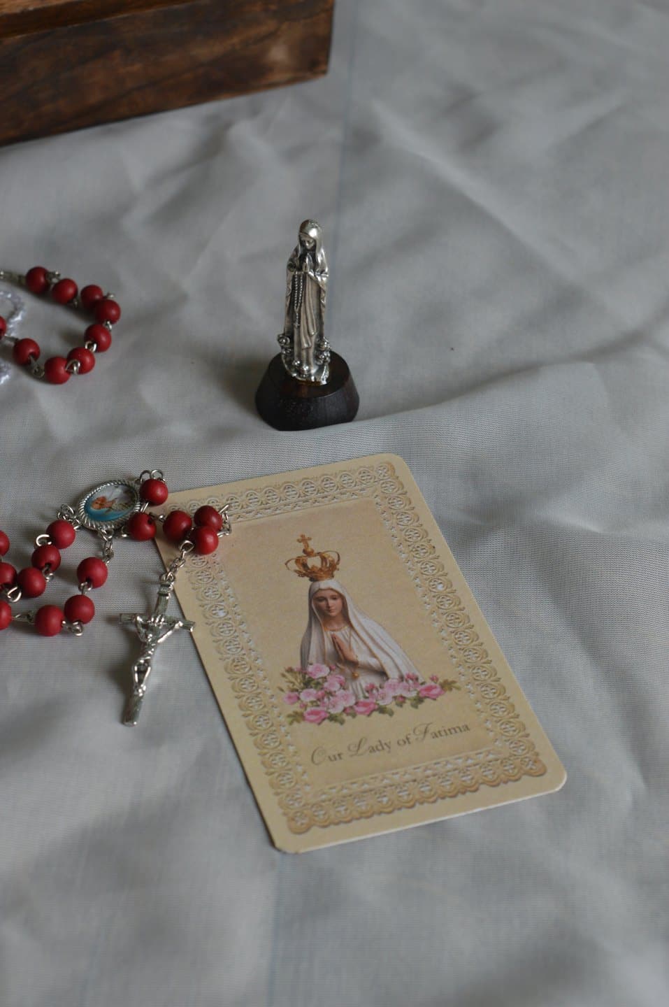 Oggetti religiosi tra cui un rosario e un santino su tessuto.