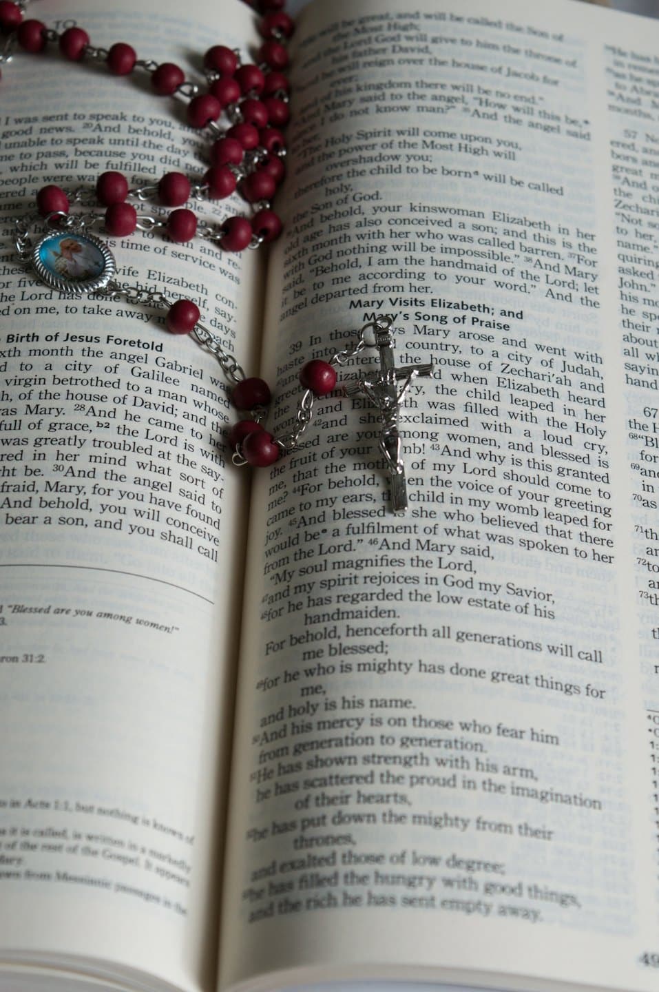 Un rosario di perle rosse posato sulle pagine aperte di un libro.