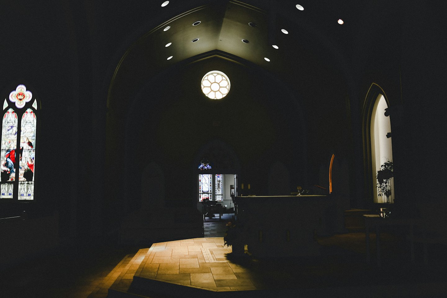 La luce del sole filtra attraverso le vetrate colorate su un pavimento piastrellato di una chiesa.