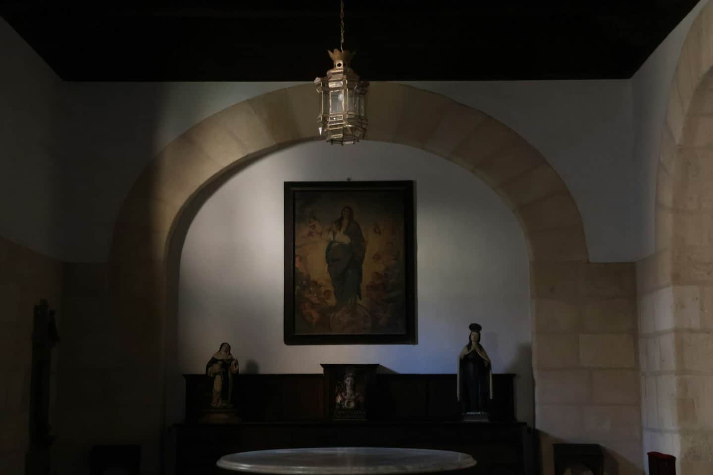 Dipinti e statue religiose esposti sotto un arco di pietra.
