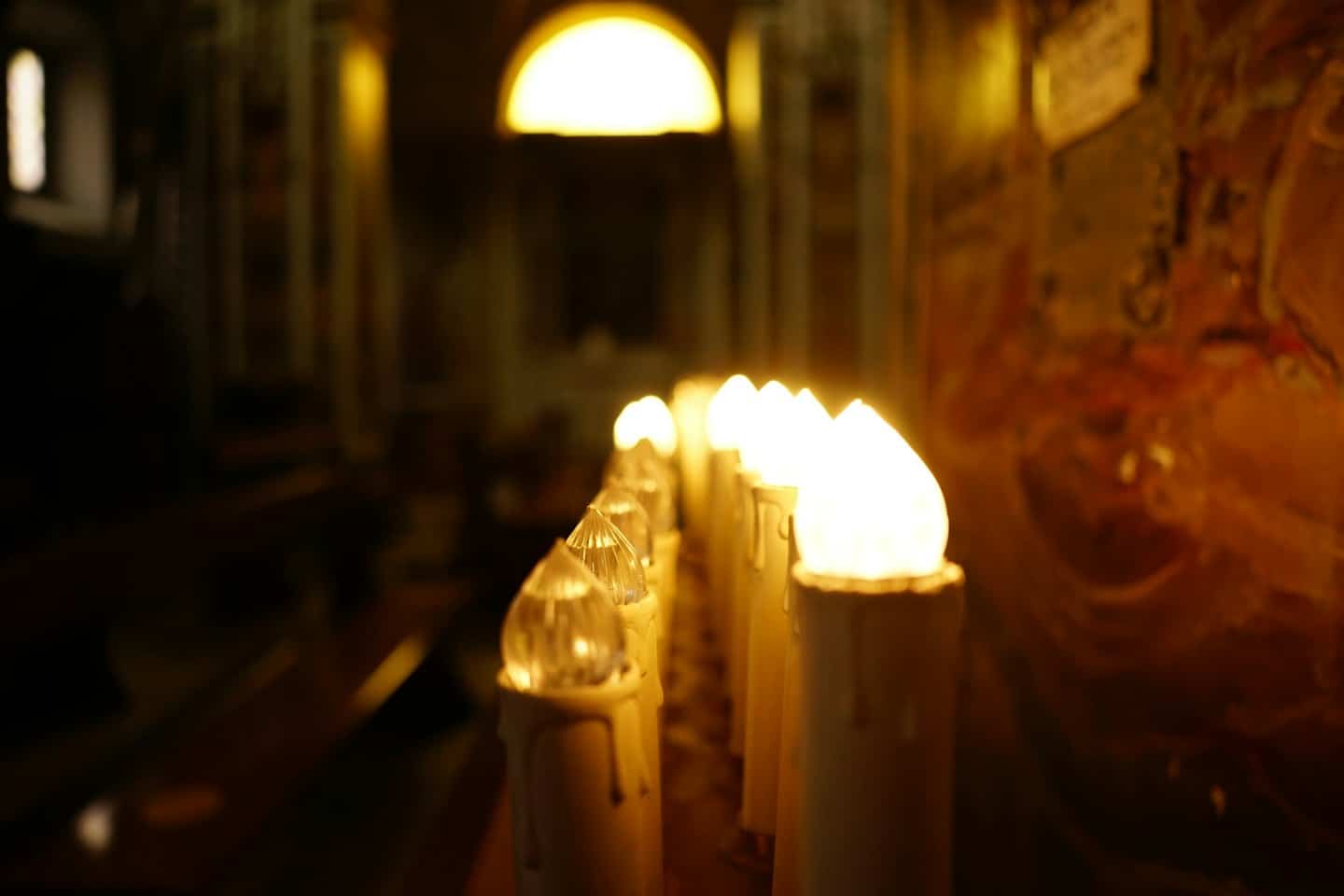 Candele artificiali luminose in un tranquillo interno di chiesa storica.